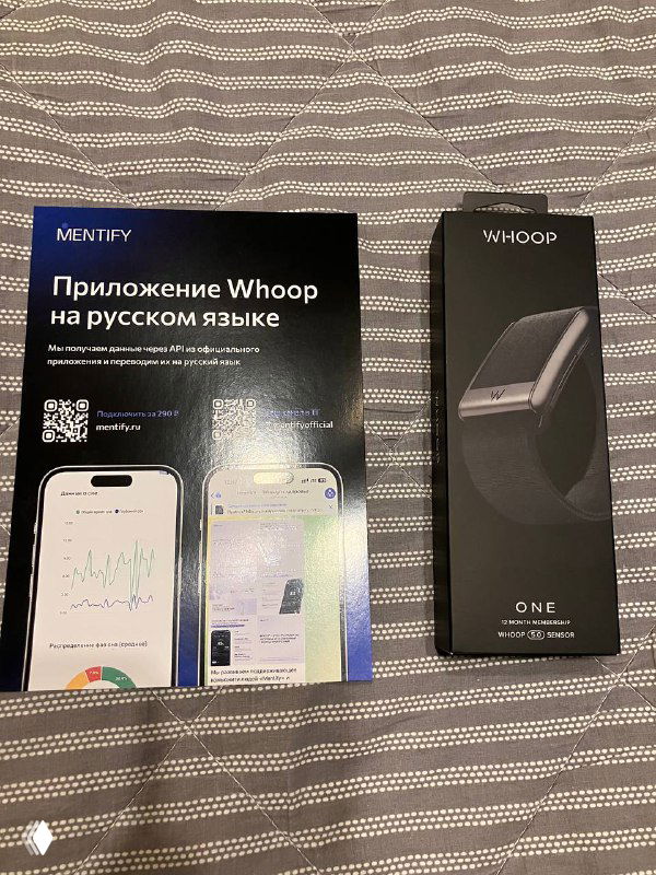 Фото упаковки Whoop 5.0 и листовки с надписью «Приложение Whoop на русском языке», коробка и фон из ткани.
