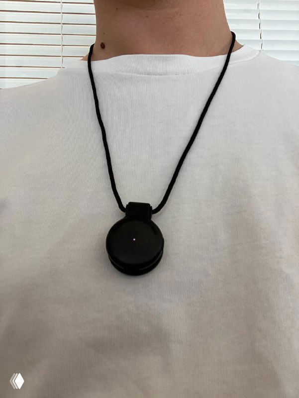 Pendant крупным планом на шнурке на груди человека: показан внешний вид устройства, минималистичный дизайн и размер относительно шеи.