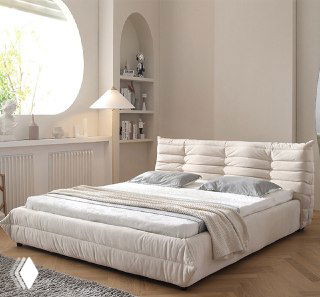 Уютная мягкая тканевая кровать светлого бежевого тона, показанная в минималистичной спальне с натуральным освещением и деревянным полом, демонстрация товара из каталога.