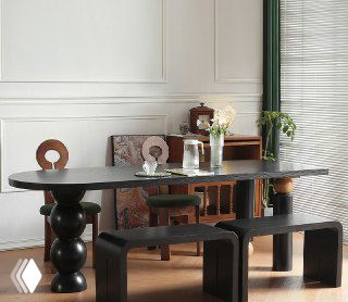 Фотография стола из ясеня в интерьерной сцене: длинная овальная столешница тёмного оттенка, массивные декоративные ножки, табуреты и предметы декора вокруг