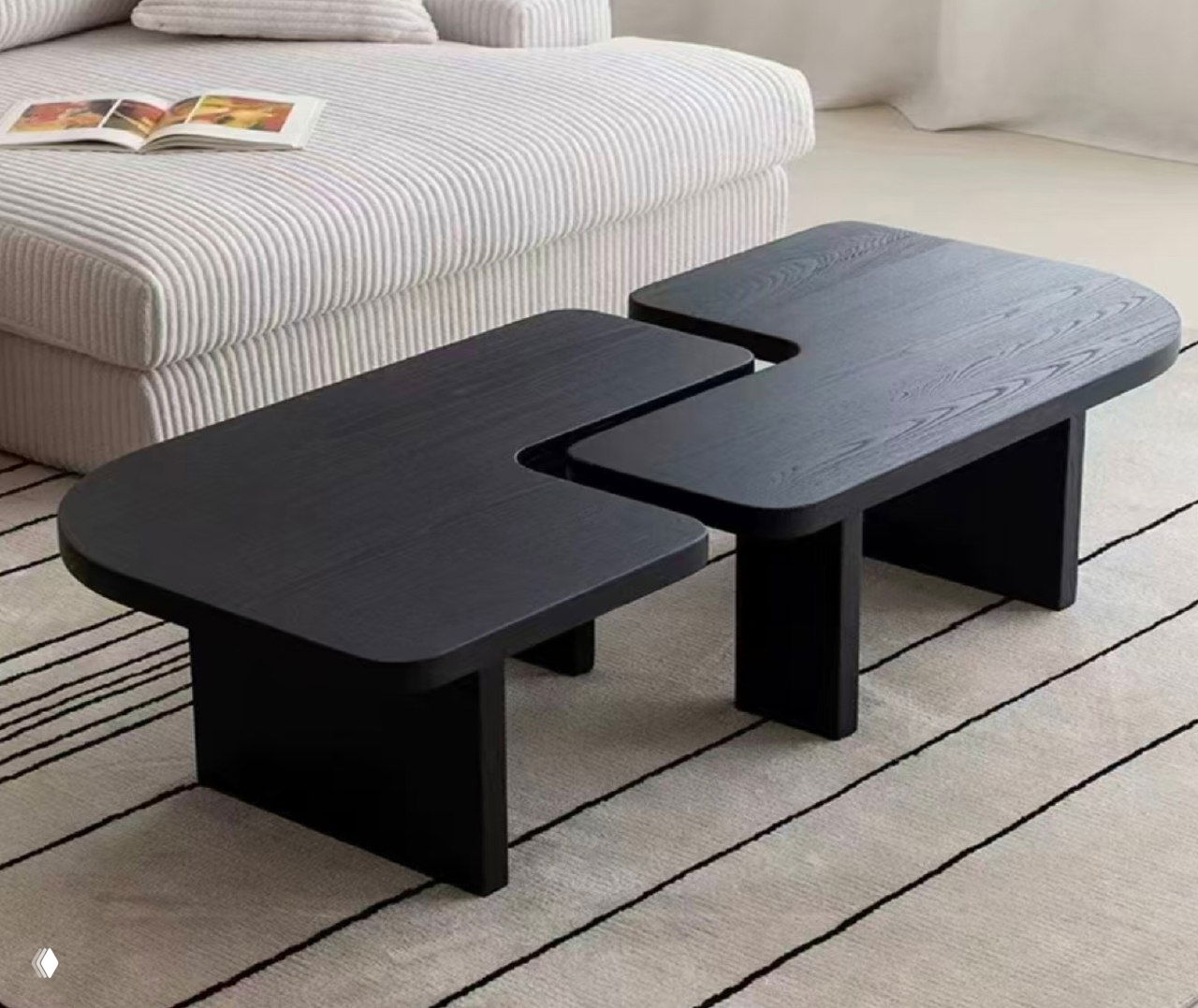 Чёрный журнальный столик из ясеня в светлом интерьере: две соединённые столешницы на низких опорах, рядом мягкий диван и ковер.