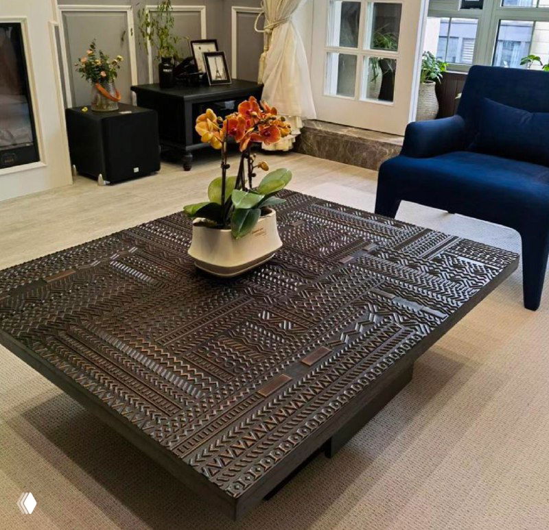 Квадратный журнальный столик из массива ясеня с декоративной резьбой по всей поверхности, расположен в гостиной интерьере.