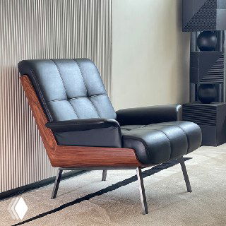 Кресло в интерьере: окрашенная деревянная спинка, мягкая губка в обивке, стальная рама и тонкие металлические ножки, нейтральный фон.