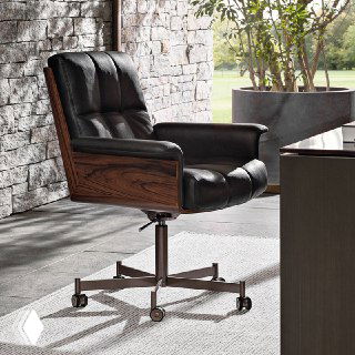 Чёрное кожаное кресло с деревянными боковинами, мягкой обивкой и металлической базой на колёсах, размещено у кирпичной стены