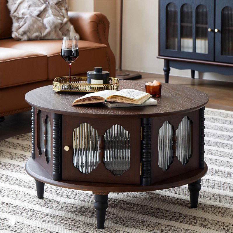 Круглый журнальный столик из массива дуба в интерьере: тёмное дерево, резные дверцы, книга и бокал на столе, диван рядом
