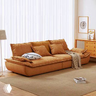 Коричневый кожаный диван Галеон в светлой комнате с занавесками и деревянной тумбой, ракурс показывает боковую часть и подушки.