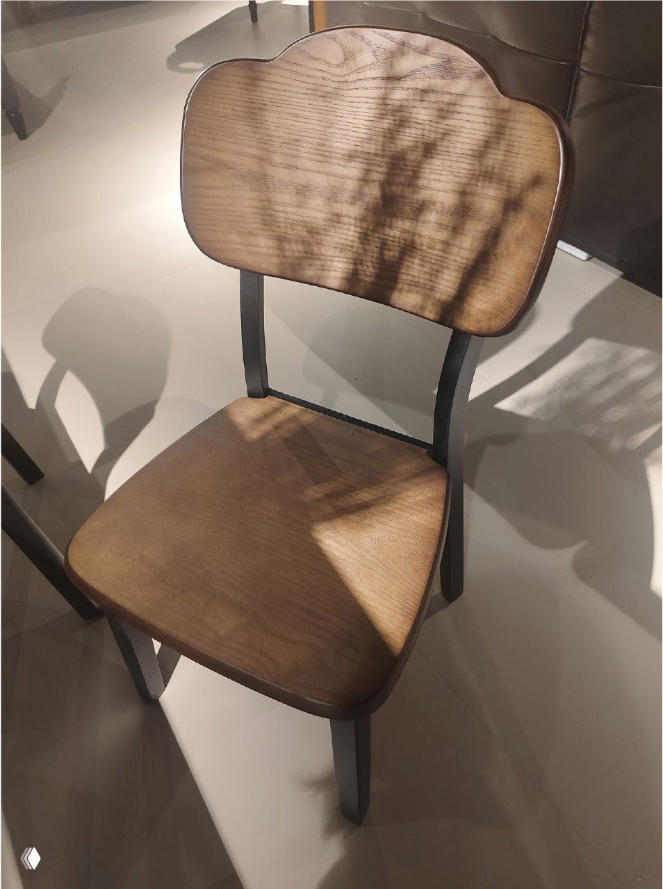 Фотография стула из массива ясеня: деревянное сиденье и спинка с выраженной текстурой, металлический каркас, вид в шоуруме.