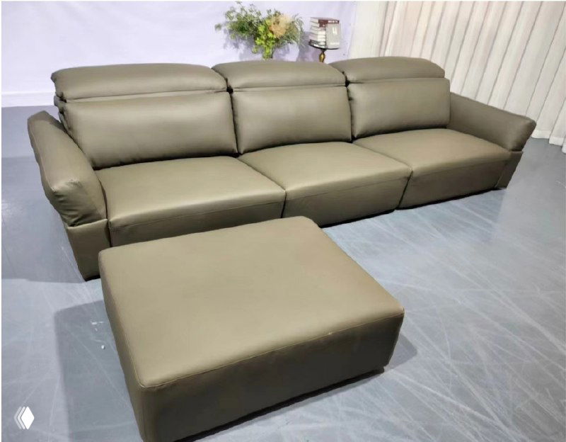 Снимок трёхместного кожаного дивана оливкового цвета с отдельным пуфом и высокой спинкой на сером полу в современном интерьере