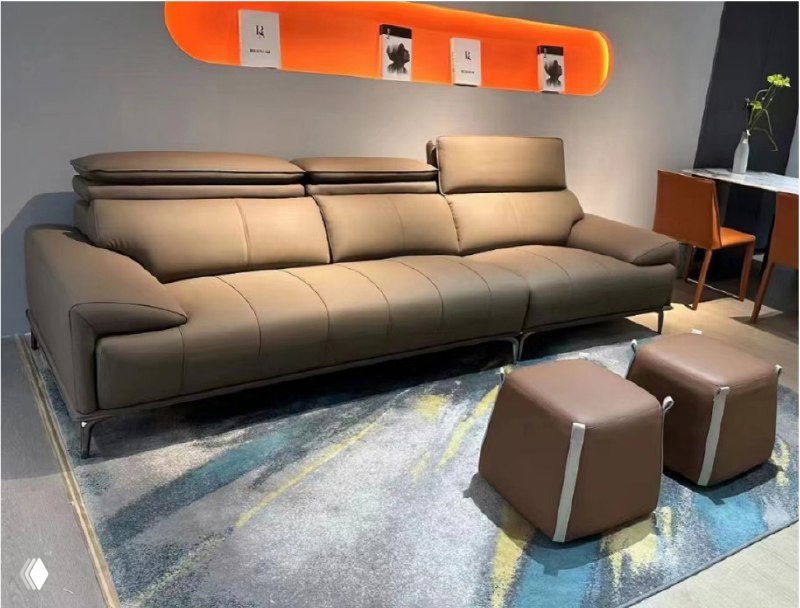 Современный коричневый кожаный диван в шоуруме: три посадочных места, два пуфика, ковер и настенная декоративная полка.