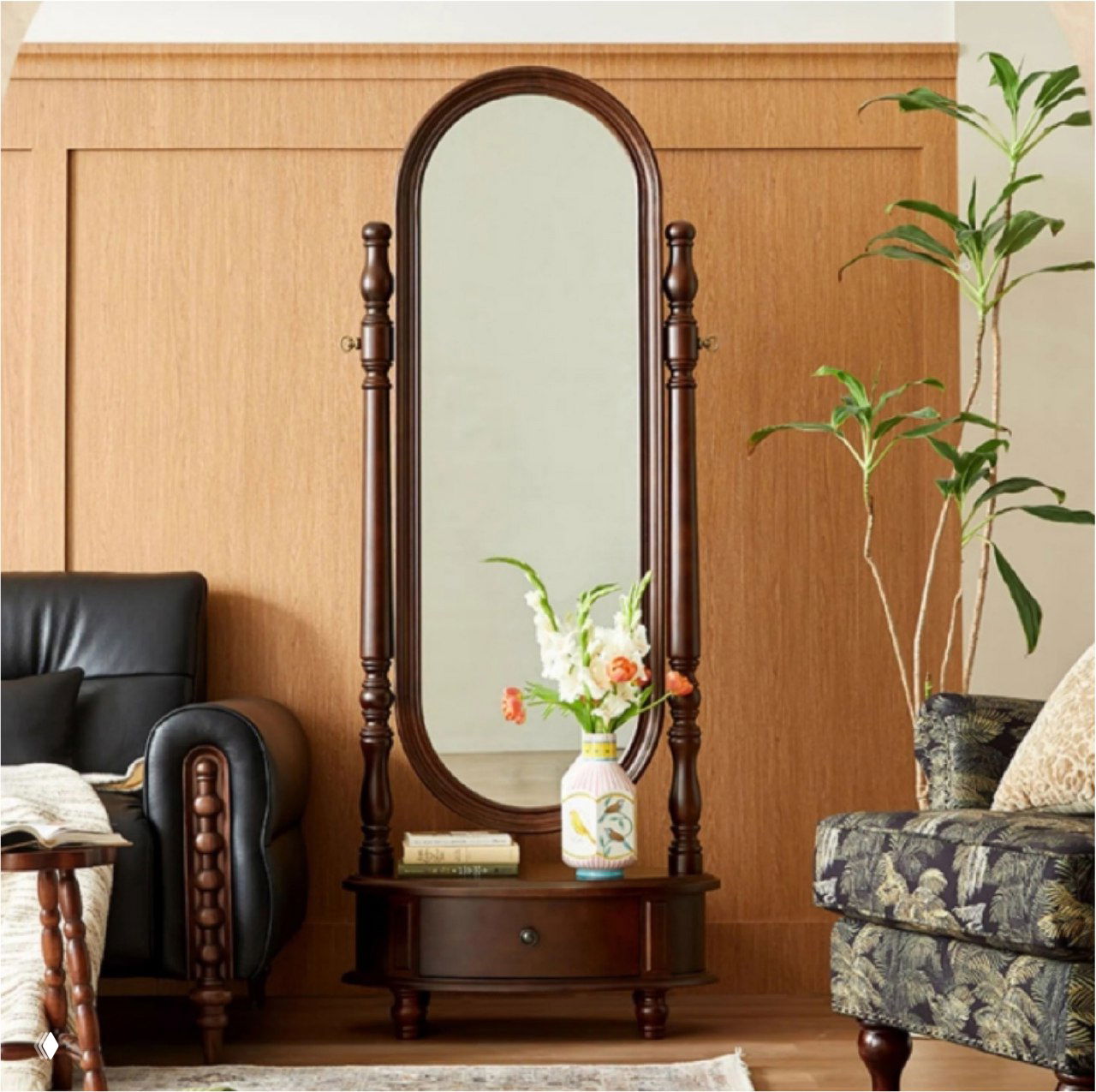 Напольное зеркало из массива дуба с овальным зеркальным полотном и выдвижным ящиком, стоит в жилом интерьере рядом с диваном, креслом и растениями.