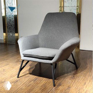 Фото серого кресла в выставочном зале: мягкая обивка, съемная подушка, подлокотники и черные металлические ножки.