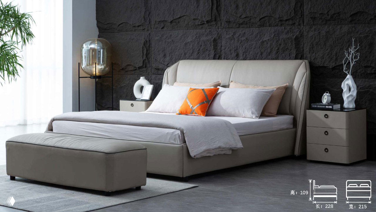 Кровать в бежевой кожаной обивке на фоне тёмной рельефной стены, пуф у изножья и прикроватные тумбы.