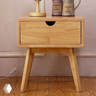 Прикроватная тумба из массива дуба на наклонных ножках, крупный план спереди, видна натуральная текстура дерева и светлая отделка.