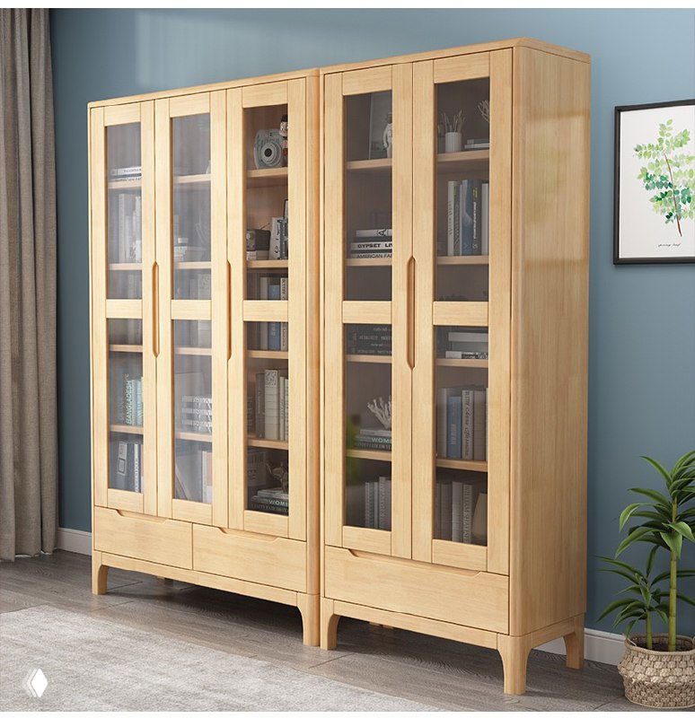 Шкаф книжный из массива дуба: светлый корпус, стеклянные дверцы, четыре секции с книгами, растение рядом