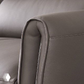 Крупный план кожаного подлокотника дивана Cowhide, показывающий строчку швов и текстуру воловьей кожи.