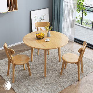 Круглый обеденный стол из светлого дуба в домашнем интерьере: стол с тремя деревянными стульями на ковре у окна.