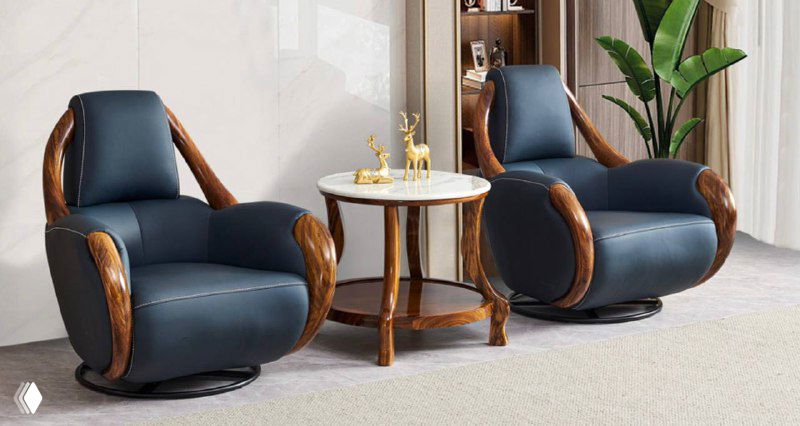 Два тёмно-синих кресла с массивными деревянными подлокотниками и небольшим круглым столиком между ними, мебель с выразительными деревянными рамами.