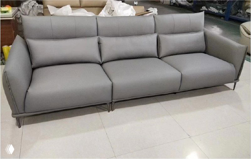 Серый трёхместный диван размером 290×100×95 с плотной обивкой, съёмными подушками и металлическими ножками на плиточном полу в шоу-руме.