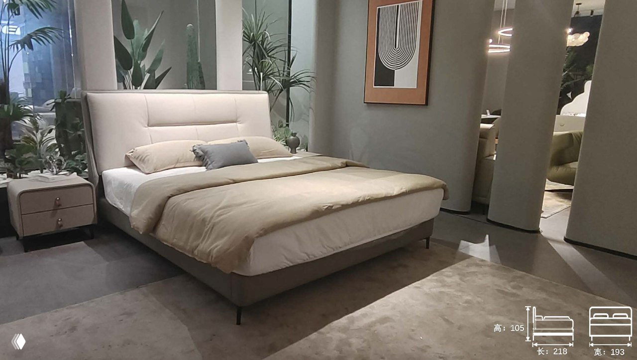 Кровать в интерьерном шоуруме: двуспальная модель с мягким изголовьем и нейтральным постельным оформлением, видны габариты и окружение комнаты.