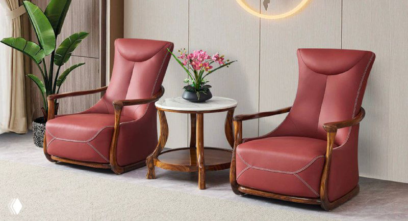 Пара пастельно-розовых кресел с изящными деревянными рамами и центральным небольшим столиком, интерьер с акцентом на древесные детали.