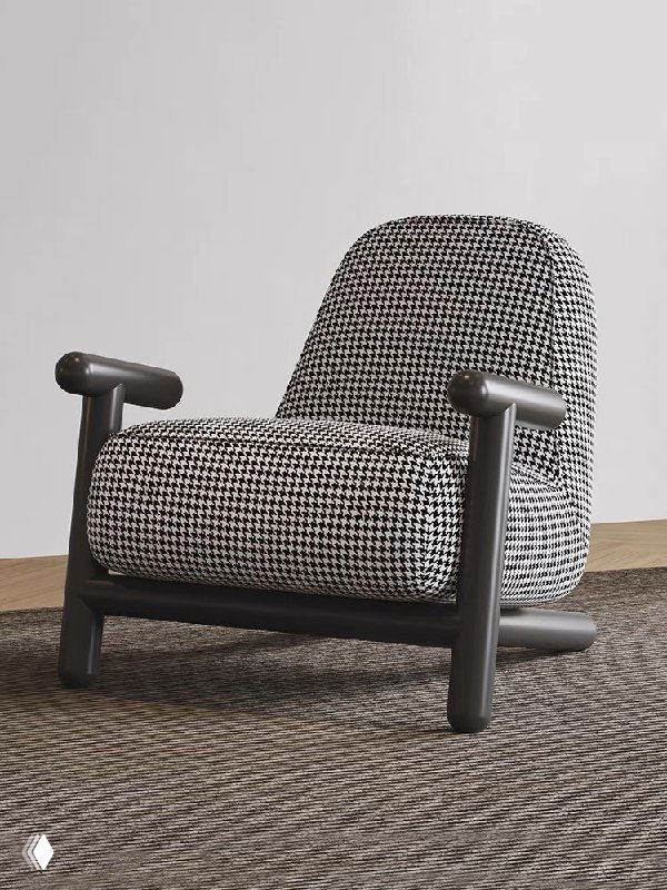 Фотография кресла на низком ясиновом каркасе с тёмно‑белой тканевой обивкой, расположено на ковре в светлой интерьерной сцене