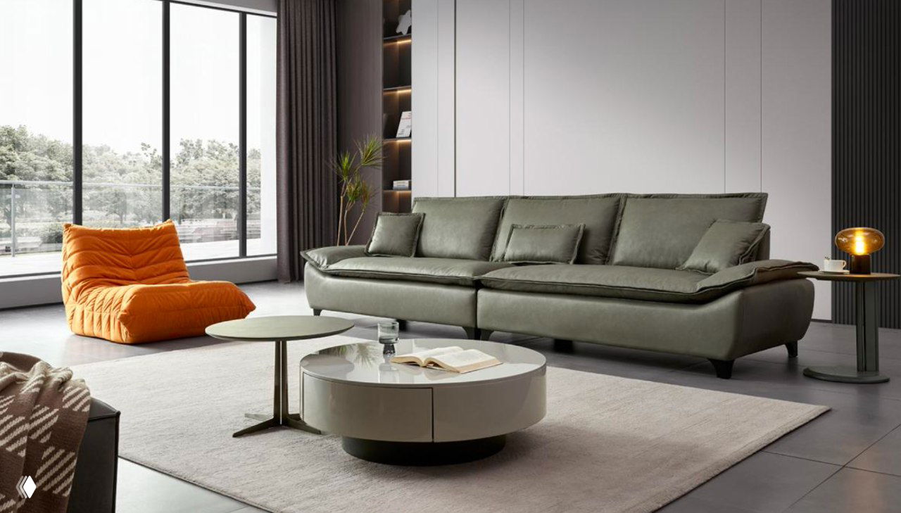 Салатово-зелёный современный кожаный диван в светлом интерьере: рядом оранжевый пуф, круглый журнальный столик и панорамное окно