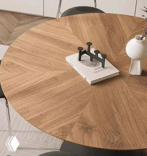 Крупный план деревянной столешницы из ясеня с радиальным рисунком древесины, на столе декоративная книга и минималистичный подсвечник.