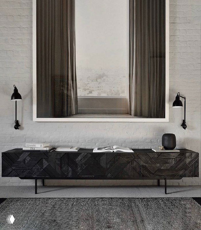 Тёмная ТВ-тумба из ясеня у стены под большим окном, низкая металлическая опора и выраженная фактура древесной поверхности в интерьере.