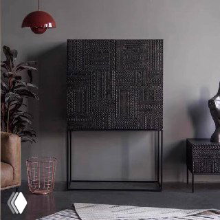 Тёмный шкафчик из массива ясеня на высоких металлических ножках в минималистичном интерьере; декоративный рельефный фасад, вид спереди в комнате.