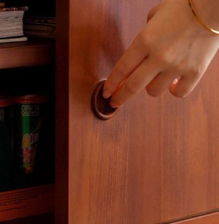 Крупный план ручки дверцы и текстуры древесины ясеня на дверце шкафа, демонстрация фурнитуры и качества отделки мебели.