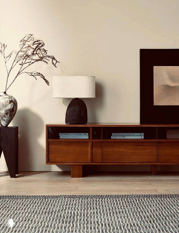 ТВ-тумба из ясеня в интерьере: ракурс с противоположной стороны, подчёркнуты пропорции тумбы, ковра и настольной лампы на фоне стены.