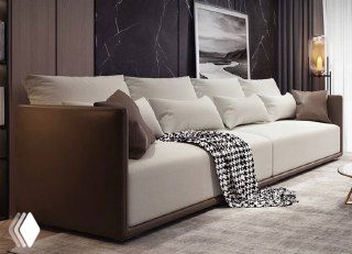 Крупный план дивана с контрастными кожаными боками и мягкими подушками на фоне декоративных картин и тёмных штор.