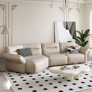 Прямой бежевый кожаный диван в элегантной комнате с белой лепниной и низким кофейным столом, интерьер в нейтральной палитре.