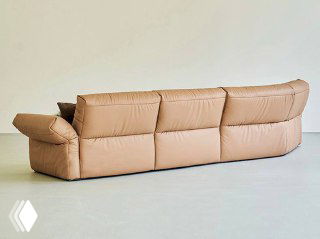 Вид сзади на коричневый кожаный диван — показан профиль, форма спинки и подушек на светлом однотонном фоне студии.