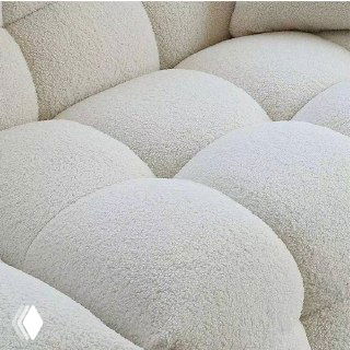 Крупный план текстуры плотной белой ткани букле на диване, вид на объёмные сегменты сиденья и стёжку, подчёркивающий фактуру обивки