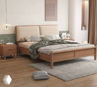 Кровать из массива ясеня в интерьерной спальне: деревянный каркас и мягкое изголовье, аккуратно застелена, виден прикроватный столик.