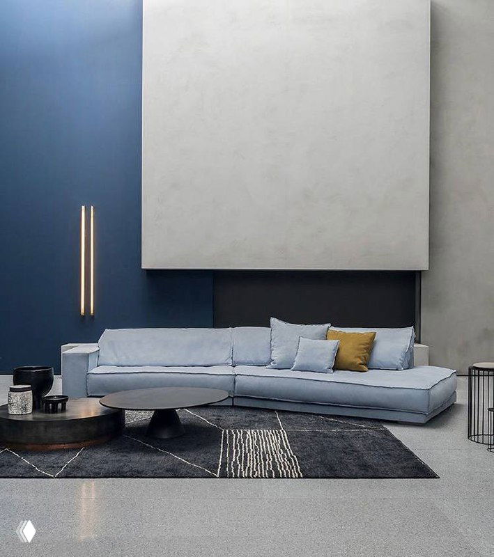 Длинный голубой модульный диван в просторном интерьере: низкая посадка, аккуратные подушки и минималистичный журнальный столик на фоне