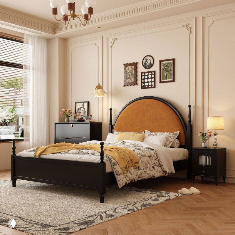 Кровать в классическом интерьере: темно-черная рама и округлое оранжевое изголовье, аккуратно заправленное постельное бельё возле окна.