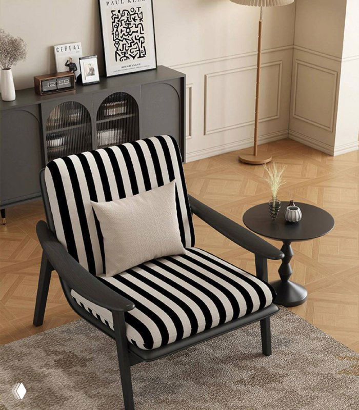 Кресло из ясеня в варианте обивки в черно‑белую полоску в интерьере с пуфом и столиком, общий ракурс, показывающий форму и пропорции модели.