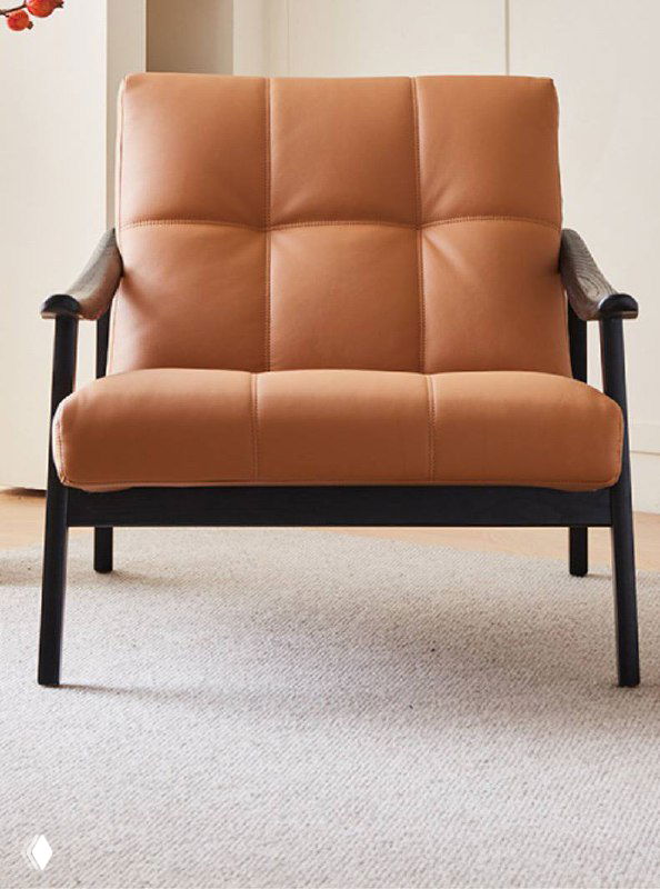 Фронтальный вид кожаного кресла из ясеня с шаговыми строчками на сиденье; видна пропорция подлокотников и расстояние до пола.