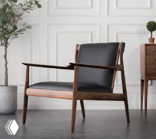 Кресло из массива ясеня с кожаной сидушкой и спинкой, крупный план под углом, окружение интерьерного стиля и декоративные растения.