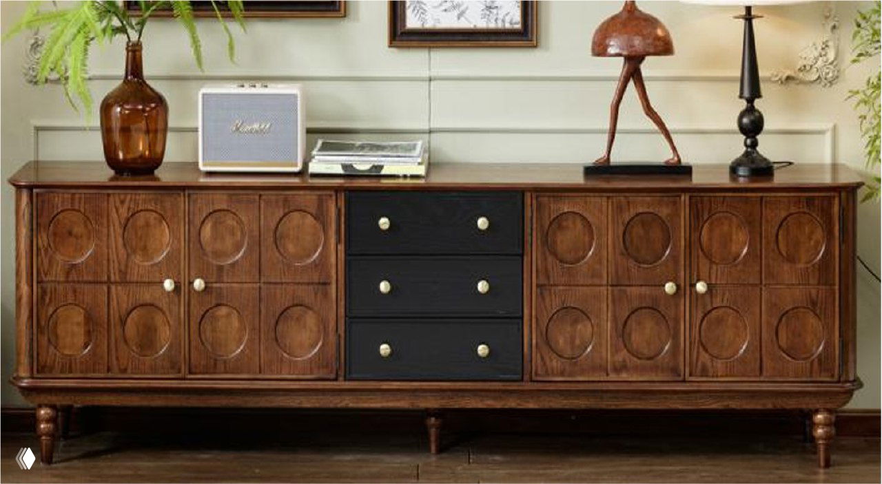 Тумба под ТВ из массива ясеня в коричневой отделке, с круглыми рельефными фасадами и тёмными выдвижными ящиками, в интерьере.