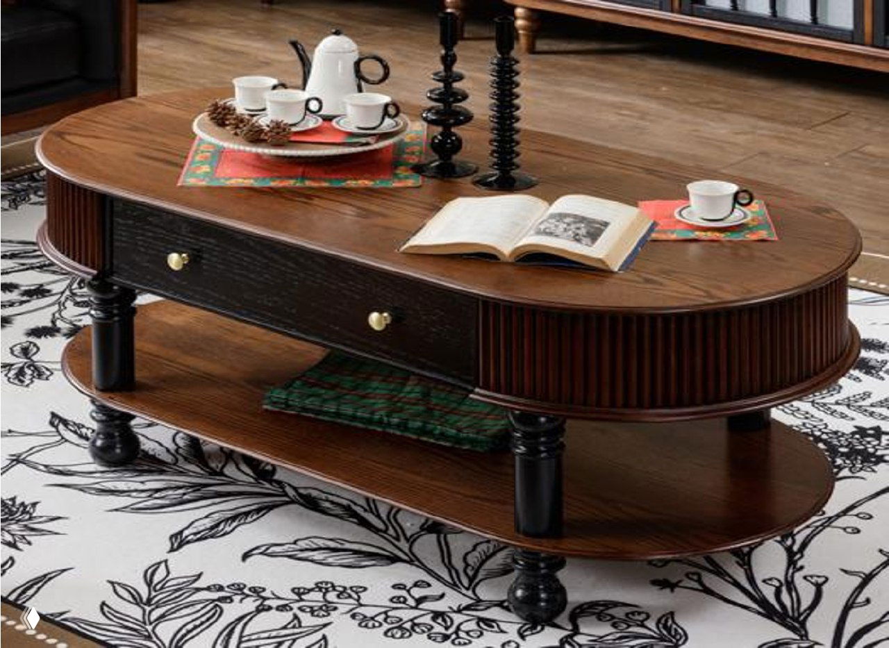 Овальный журнальный столик из массива ясеня на тёмных резных ножках, с чайным сервизом и открытой книгой в интерьерной сцене.