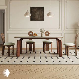 Фото обеденного стола из массива ясеня в светлом интерьере: длинный деревянный стол с закруглёнными массивными ножками и стульями на фоне декоративных панелей.