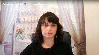 Женщина сидит перед камерой в домашнем кабинете: шторы и декоративная панорама на фоне; кадр из видеоэфира по психологии отношений и работе с дефицитами.