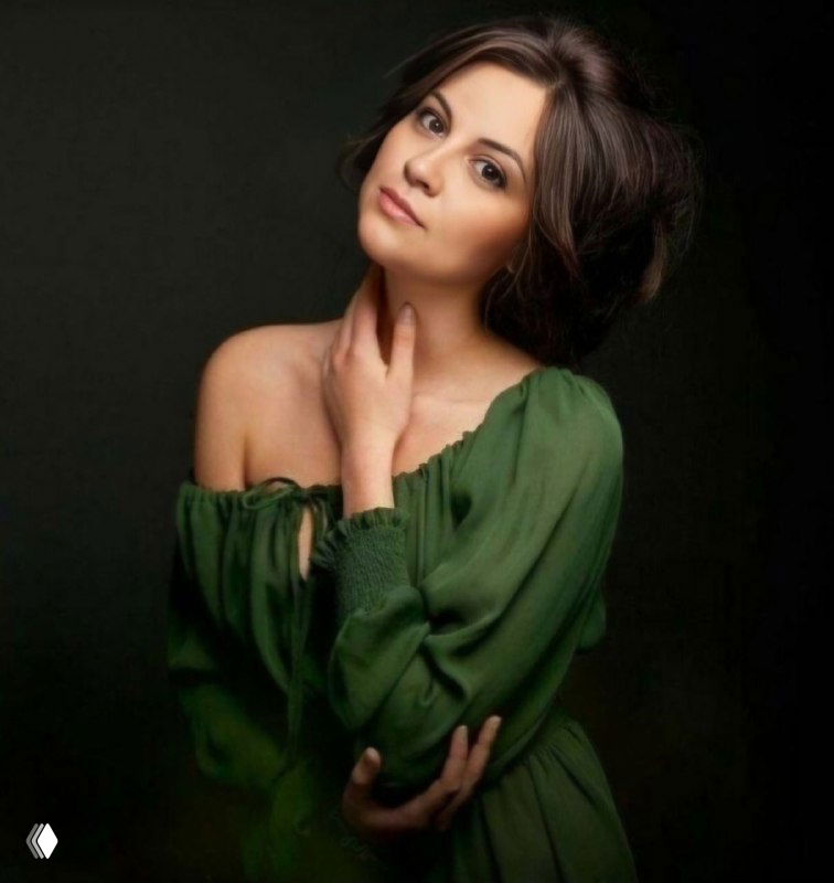 Портрет женщины в зелёном платье на тёмном фоне, задумчивое выражение лица и спокойная поза, студийная подсветка