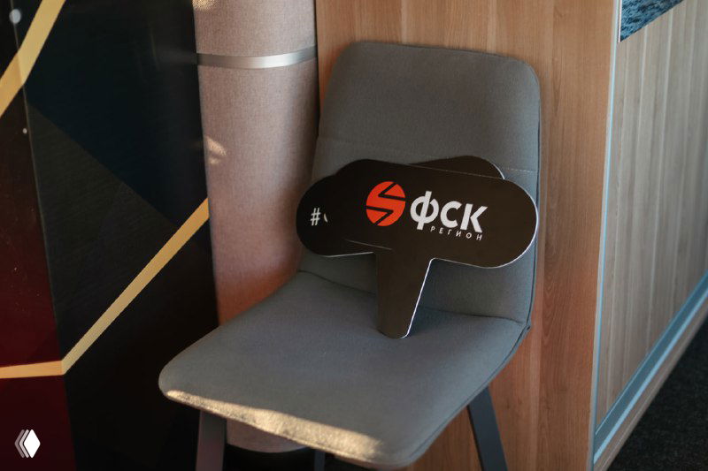 Рекламный реквизит с логотипом застройщика на стуле внутри презентационной зоны яхты, деталь фирменного оформления мероприятия.