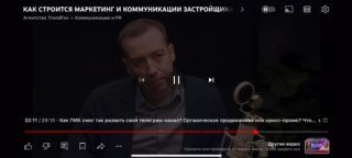 Кадр из видео: мужчина на сцене в студии говорит о маркетинге и самых эффективных каналах для посевов в недвижимости.