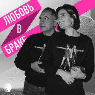 Чёрно‑белая фотография улыбающейся пары в обнимку: муж и жена стоят рядом на фоне графики и яркого розового баннера.