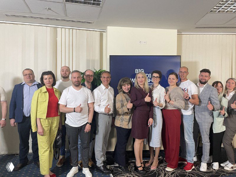 Групповое фото команды и представителей клиники на сцене или перед экраном, показывающее результат совместной работы и офлайн-мероприятие с участниками проекта.